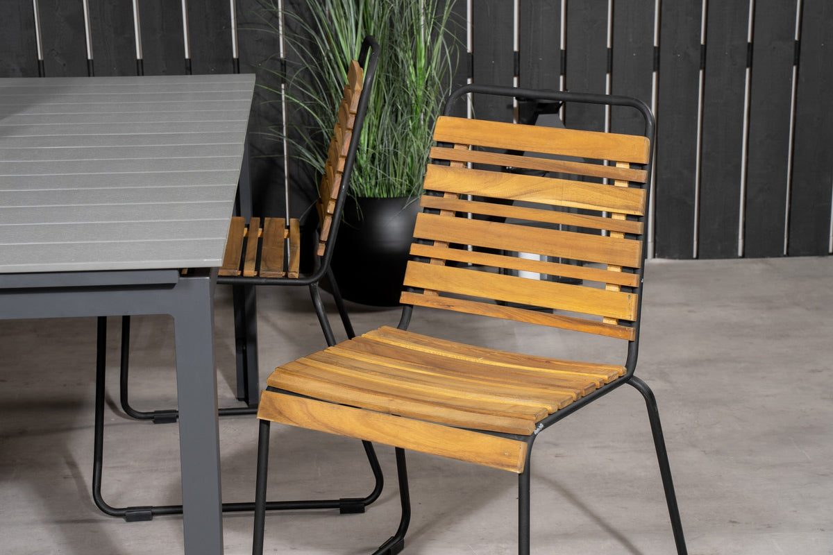Rechteckiger Gartentisch mit grauer Aintwood-Tischplatte und schwarzem Stahlgestell, daneben zwei Esszimmerstühle aus Aintwood und Aluminium in Natur.