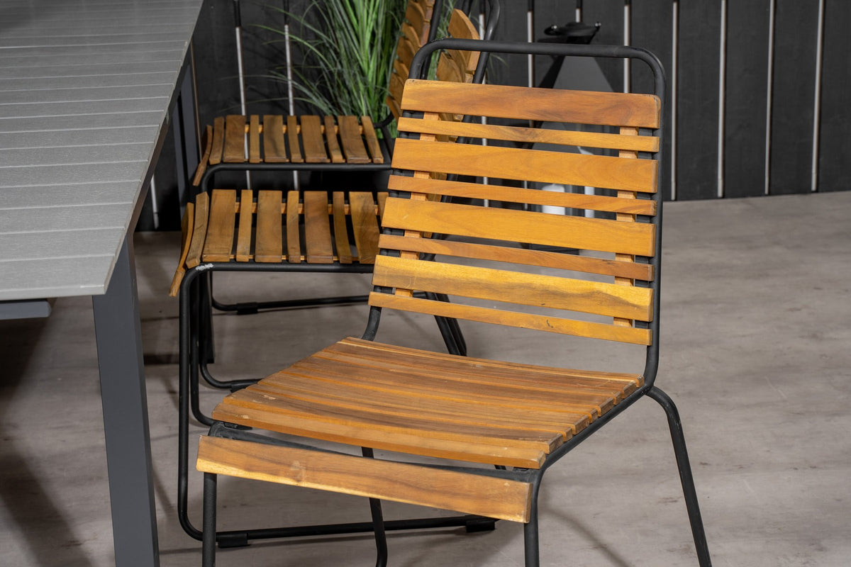 Rechteckiger Gartentisch mit grauer Aintwood-Tischplatte und schwarzem Stahlgestell, daneben zwei Esszimmerstühle aus Aintwood und Aluminium in Natur.