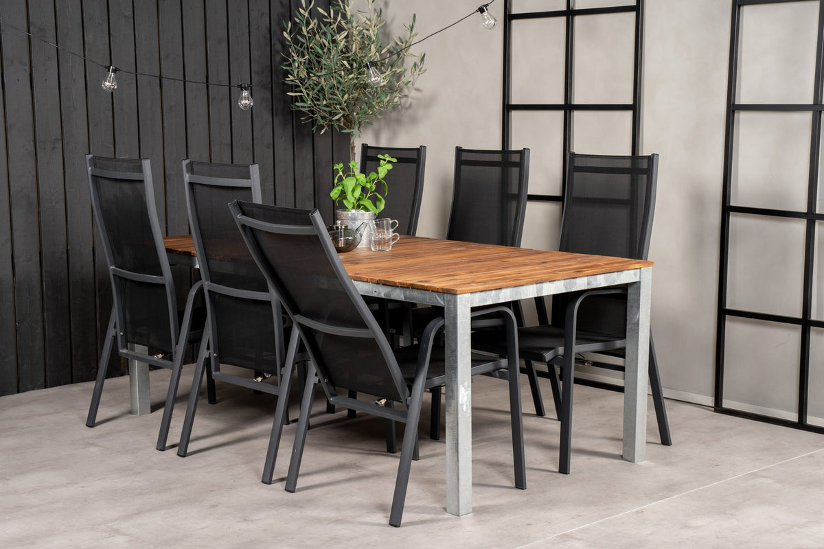 Zwei schwarze Relaxsessel aus Akazie und Stahl neben einem rechteckigen Esstisch mit Akazie-Tischplatte in Natur und Aluminiumbeinen.