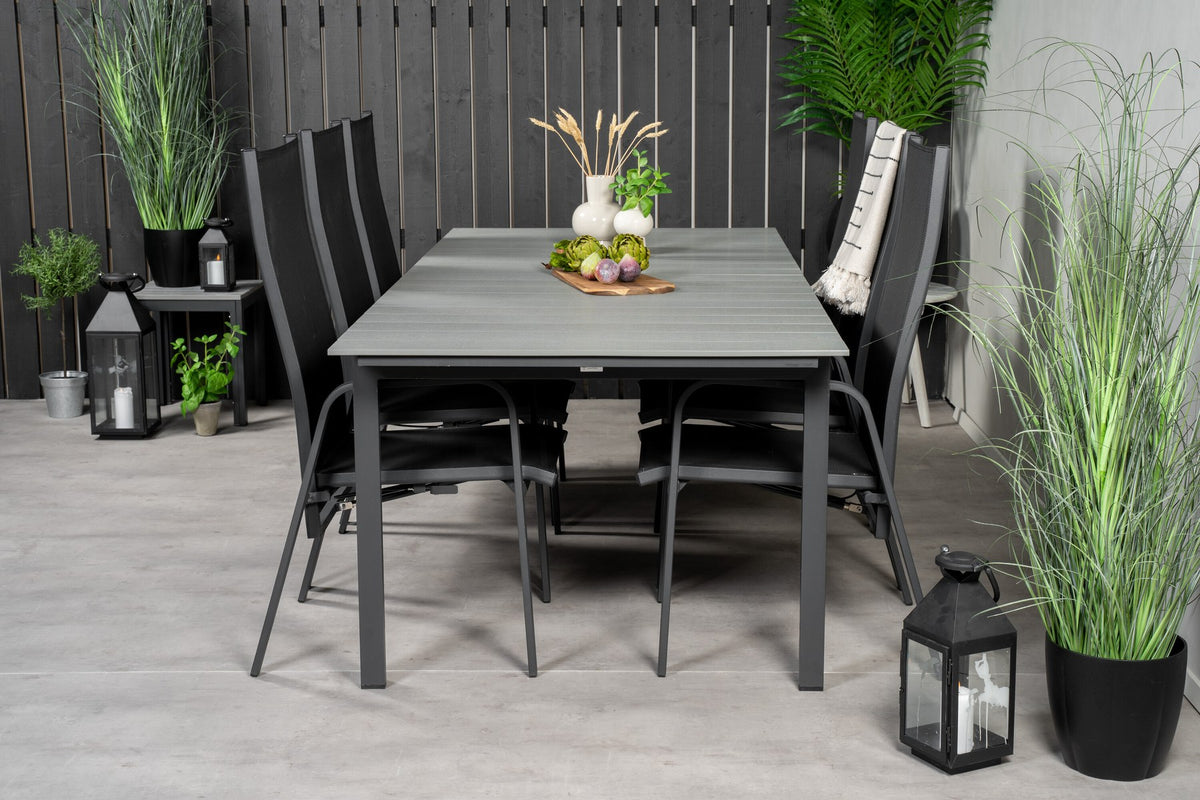 Rechteckiger Gartentisch mit grauer Aintwood-Platte und Aluminiumgestell, daneben zwei stapelbare Copacabana-Relaxsessel in Schwarz.