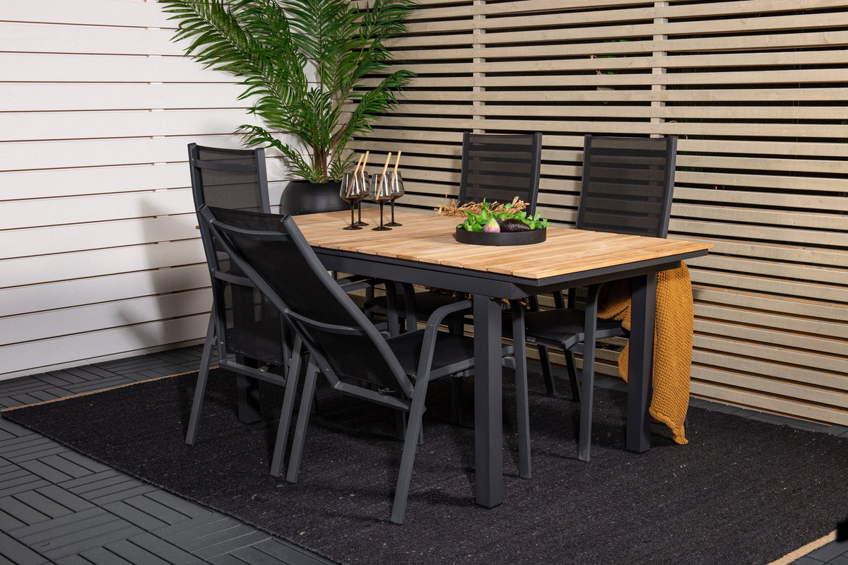 Zwei schwarze Relaxsessel Copacabana aus Aluminium mit Pulverbeschichtung neben rechteckigem Teak-Esstisch Mexico in Natur, Gartenmöbel-Set.