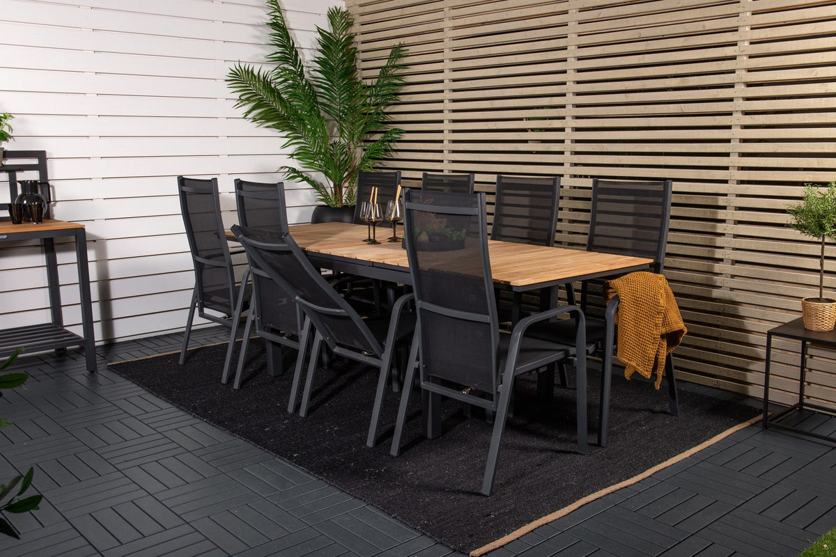 Zwei schwarze Relaxsessel Copacabana aus Aluminium mit Pulverbeschichtung neben rechteckigem Teak-Esstisch Mexico in Natur, Gartenmöbel-Set.