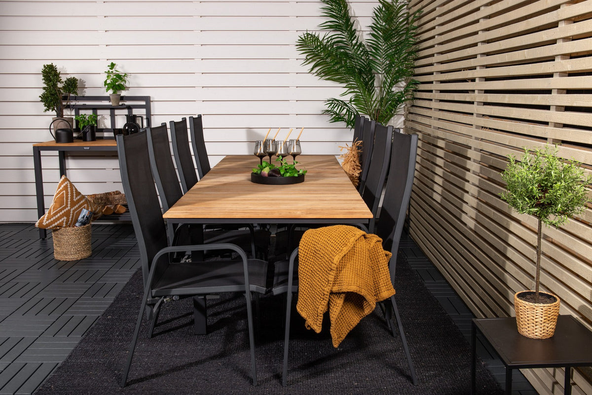 Zwei schwarze Relaxsessel Copacabana aus Aluminium mit Pulverbeschichtung neben rechteckigem Teak-Esstisch Mexico in Natur, Gartenmöbel-Set.