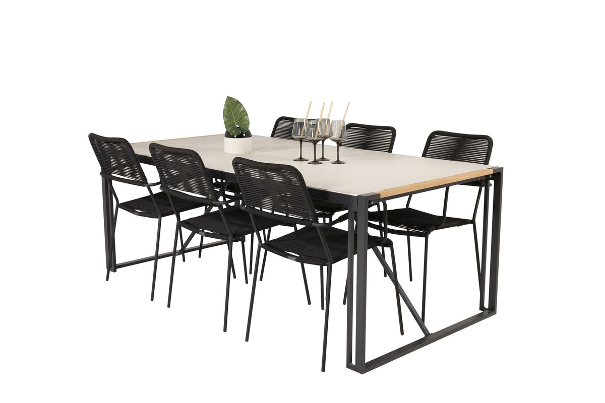 Zwei schwarze Esszimmerstühle mit geflochtener Seilsitzfläche und Aluminiumgestell neben rechteckigem Esstisch mit Glas-Teak-Platte und Stahlbeinen.