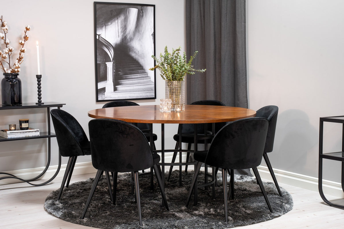 Runder Esstisch ⌀140 cm mit brauner Tischplatte aus MDF und Furnier, Stahlbeine, dazu zwei schwarze Velvet-Stühle mit pulverbeschichtetem Gestell.