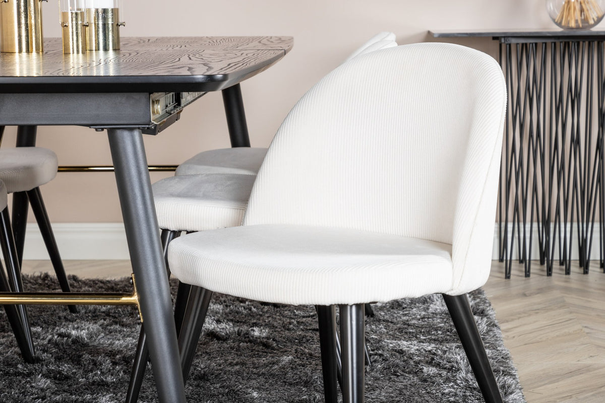 Rechteckiger Esstisch mit schwarzer MDF-Platte und Stahlbeinen, daneben zwei gepolsterte Esszimmerstühle in Creme mit Stahlgestell.