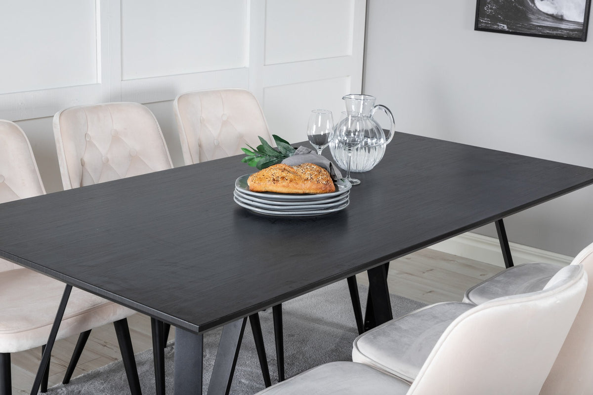 Rechteckiger Esstisch aus MDF mit schwarzer Tischplatte und Stahlbeinen, daneben zwei gepolsterte Esszimmerstühle in Beige mit schwarzem Gestell.