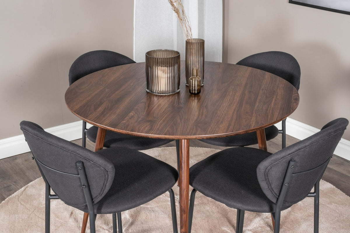 Zwei schwarze Esszimmerstühle aus MDF und Stahl neben einem runden Esstisch mit Nussbaum-Tischplatte, Durchmesser 100 cm.