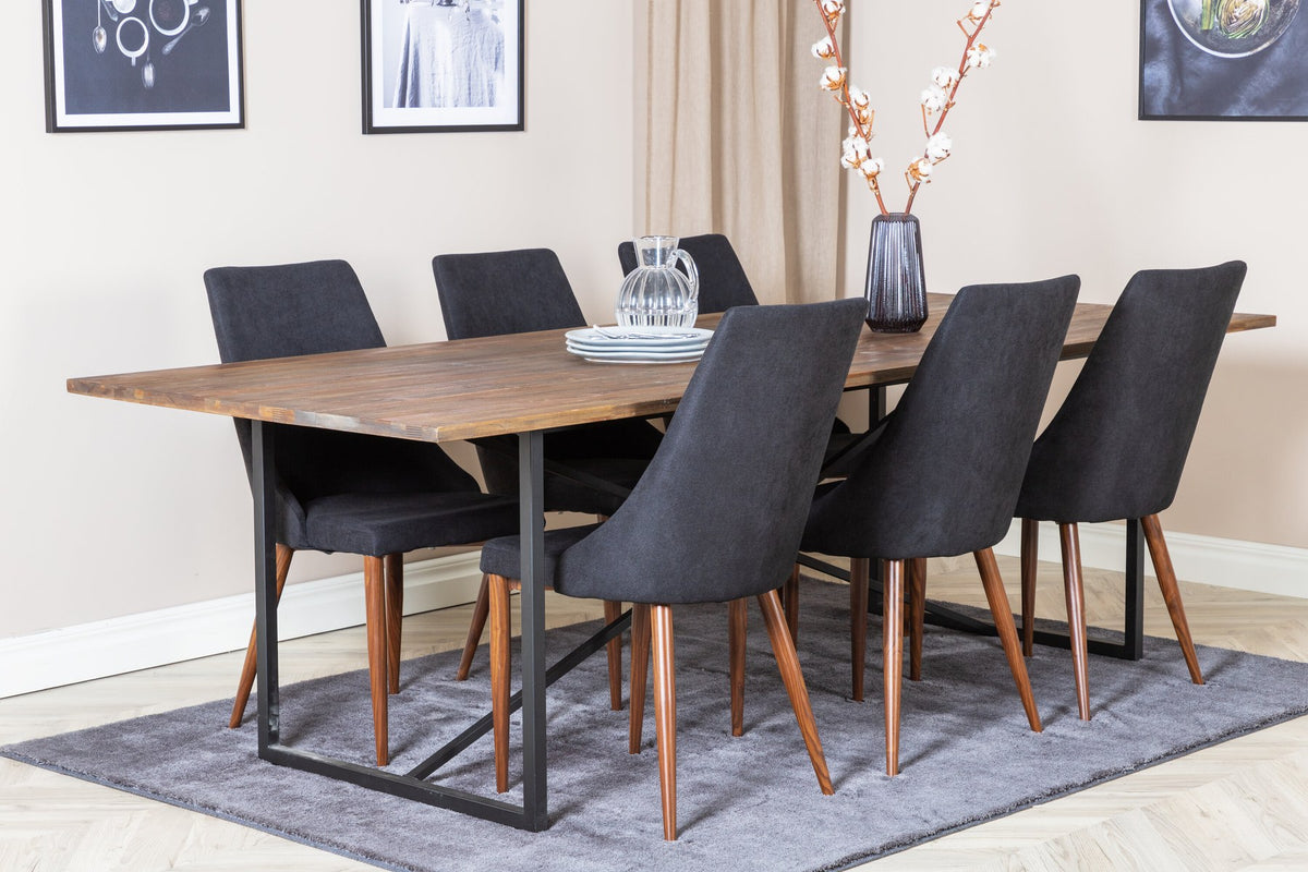 Zwei schwarze Esszimmerstühle mit Stahlgestell und Polsterbezug sowie rechteckiger Esstisch aus Teakholz mit Stahlbeinen, Farbe Natur.