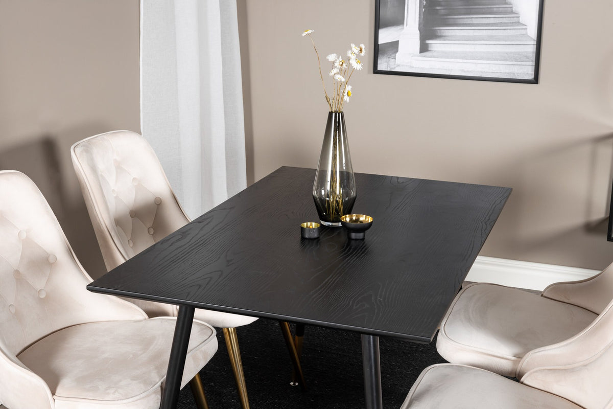 Rechteckiger Esstisch mit schwarzer MDF-Tischplatte und Stahlbeinen, daneben zwei gepolsterte Stühle in Beige mit Messing-Gestell.