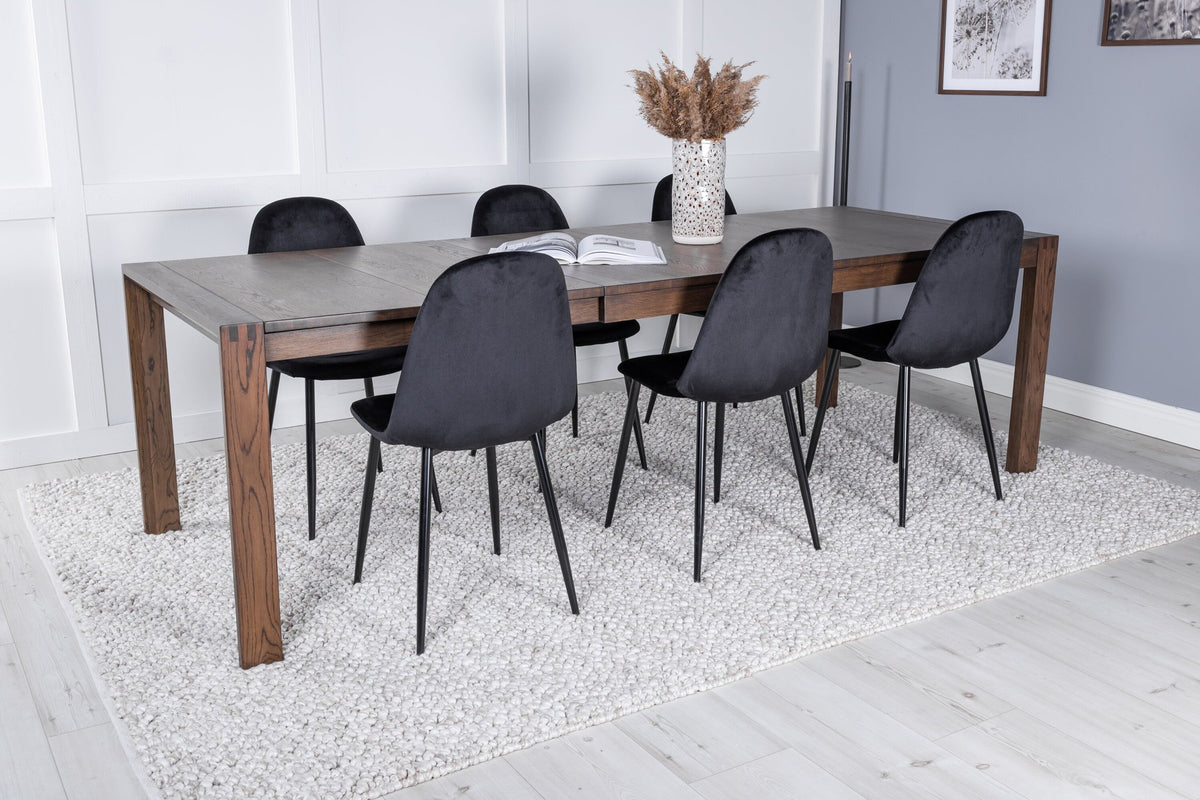 Rechteckiger Esstisch aus Eiche in Natur mit ausziehbarer Platte, dazu zwei schwarze Esszimmerstühle mit gepolsterter Sitzfläche von Venture Home.