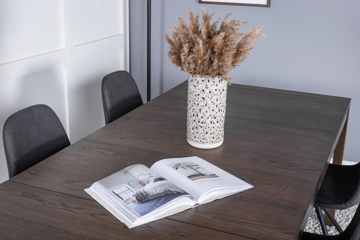 Rechteckiger Esstisch aus Eiche in Natur mit ausziehbarer Platte, dazu zwei schwarze Esszimmerstühle mit gepolsterter Sitzfläche von Venture Home.