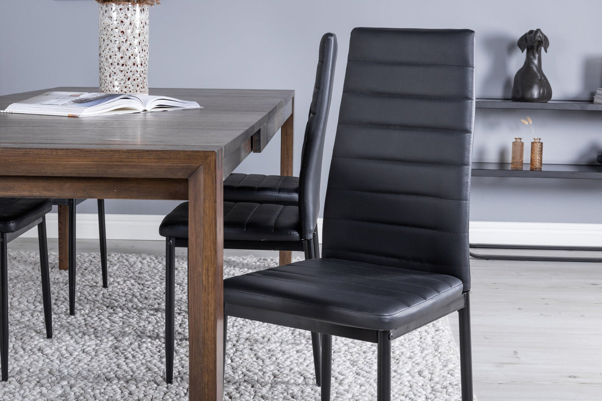 Rechteckiger Esstisch aus Eiche in Naturfarbe mit Stahlbeinen, daneben zwei schwarze Esszimmerstühle mit pulverbeschichteter Oberfläche.