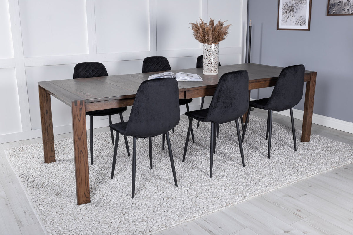 Rechteckiger Esstisch aus Eiche in Natur mit ausziehbarer Platte, dazu zwei schwarze Esszimmerstühle mit gepolsterter Sitzfläche von Venture Home.
