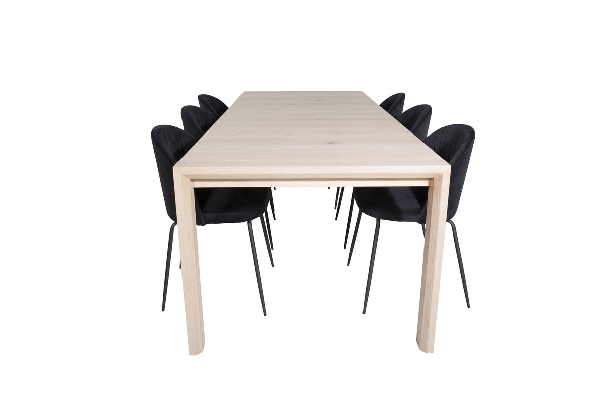Rechteckiger Esstisch aus Eiche mit weissgelaugter Tischplatte, kombiniert mit zwei schwarzen Esszimmerstühlen im skandinavischen Design.