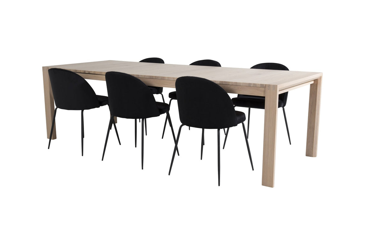 Rechteckiger Esstisch aus Eiche mit weissgelaugter Tischplatte, kombiniert mit zwei schwarzen Esszimmerstühlen im skandinavischen Design.