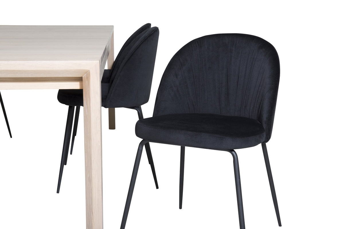Rechteckiger Esstisch aus Eiche mit weissgelaugter Tischplatte, kombiniert mit zwei schwarzen Esszimmerstühlen im skandinavischen Design.