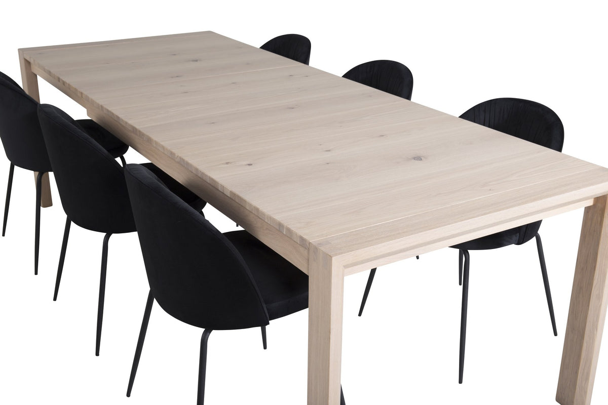 Rechteckiger Esstisch aus Eiche mit weissgelaugter Tischplatte, kombiniert mit zwei schwarzen Esszimmerstühlen im skandinavischen Design.