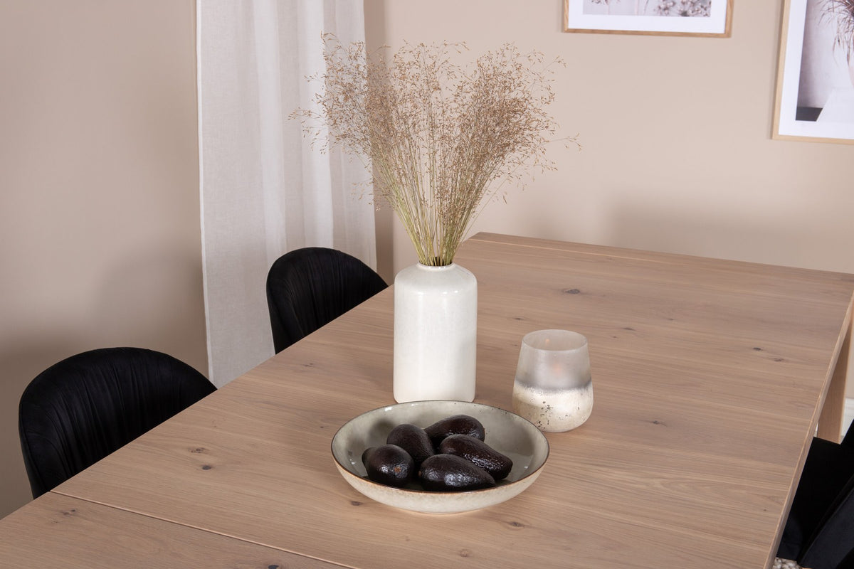 Rechteckiger Esstisch aus Eiche mit weissgelaugter Tischplatte, kombiniert mit zwei schwarzen Esszimmerstühlen im skandinavischen Design.
