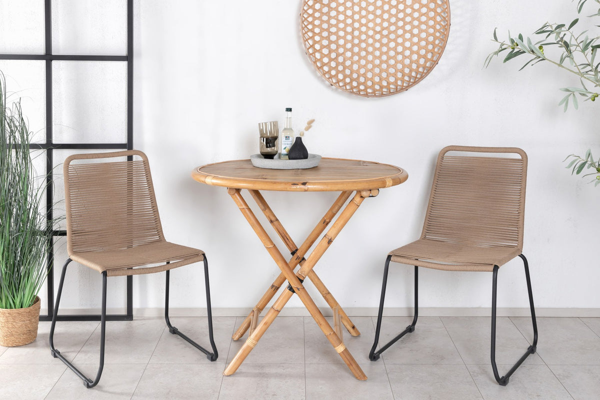 Runder Cafétisch aus Bambus mit Stahlbeinen in Natur, daneben zwei stapelbare Stühle aus Bambus und Rattan in Braun, Gartentischset.