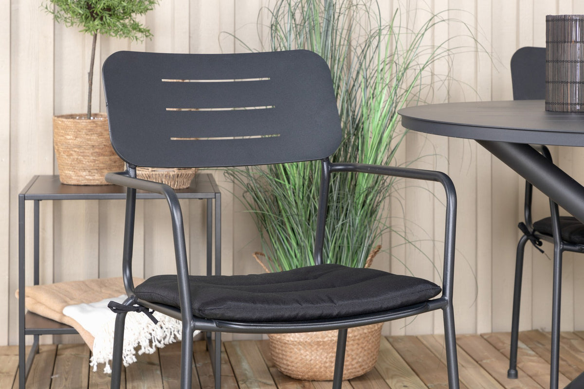 Zwei schwarze Aluminium-Stühle mit Armlehnen und Polyesterbezug neben rundem schwarzem Aluminium-Esstisch mit 120 cm Durchmesser im Freien.