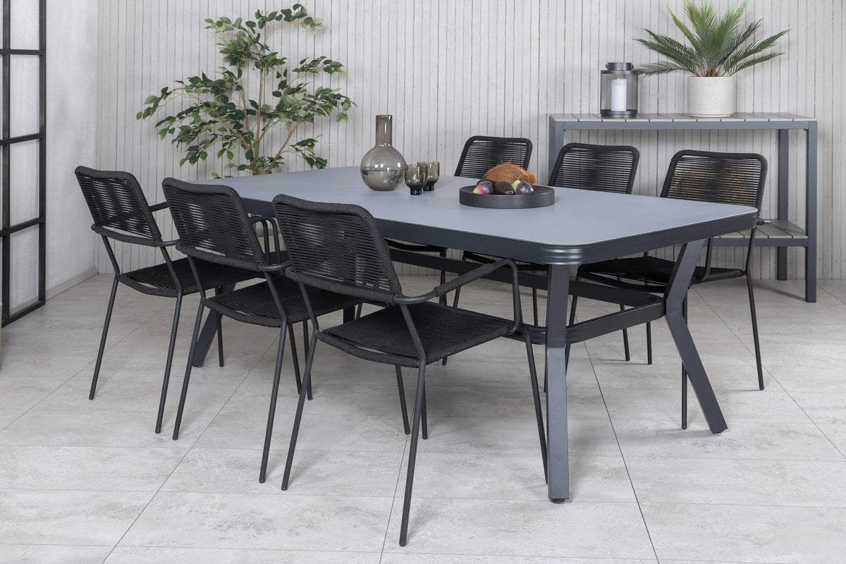 Rechteckiger Esstisch mit schwarzer Glasplatte und Stahlbeinen, daneben zwei schwarze Stühle mit Textilene-Bezug, Gartenmöbel-Set von Venture Home.