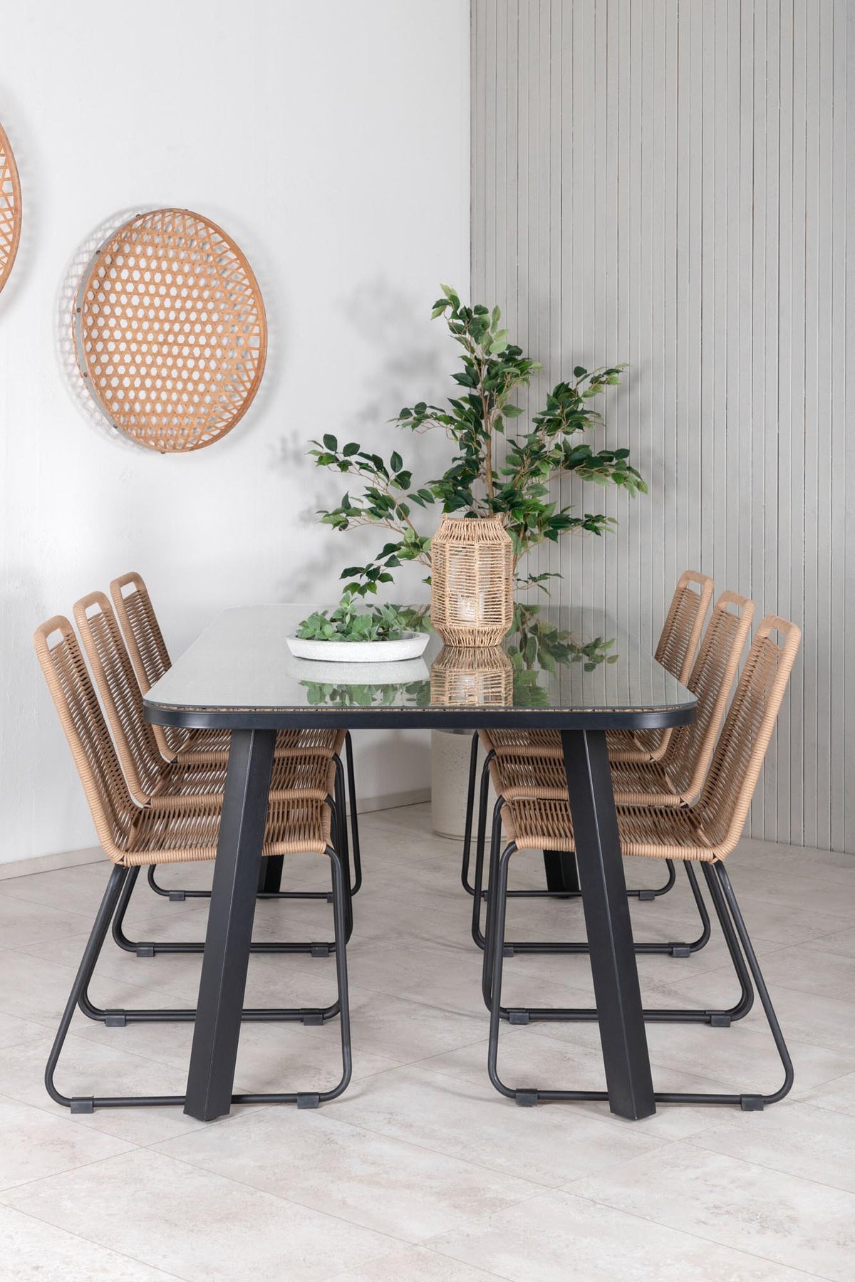 Gartentischset Paola mit schwarzem Stahlgestell und Weidengeflecht-Tischplatte sowie sechs stapelbaren Lindos-Stühlen aus schwarzem Aluminium und Polyesterseil.