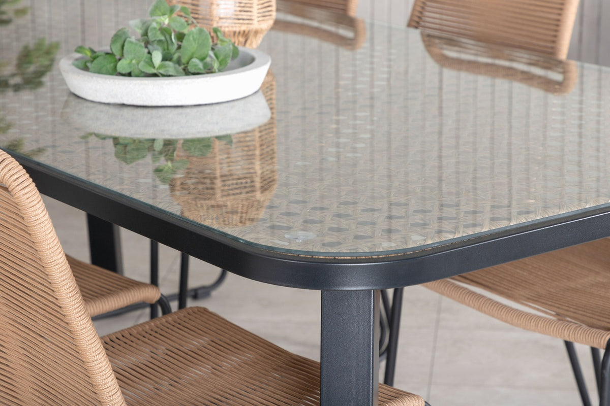 Gartentischset Paola mit schwarzem Stahlgestell und Weidengeflecht-Tischplatte sowie sechs stapelbaren Lindos-Stühlen aus schwarzem Aluminium und Polyesterseil.