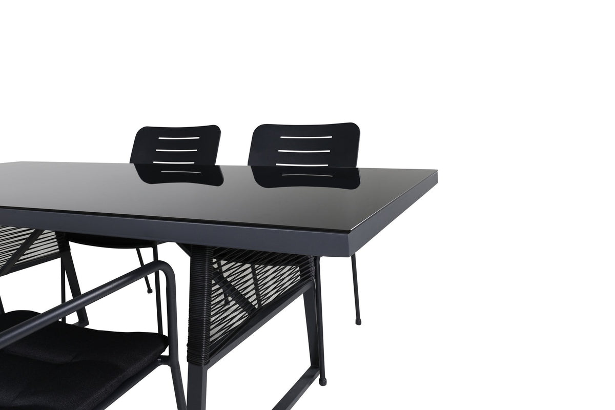 Rechteckiger Esstisch mit schwarzer Glasplatte und Aluminiumgestell sowie zwei stapelbare Stühle mit Geflecht-Bezug in Schwarz.
