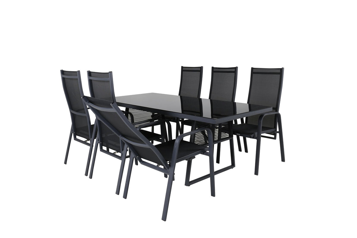 Foto eines rechteckigen Esstisches aus schwarzem Glas mit Aluminiumbeinen und zwei schwarzen Relaxsesseln aus Geflecht im Freien.