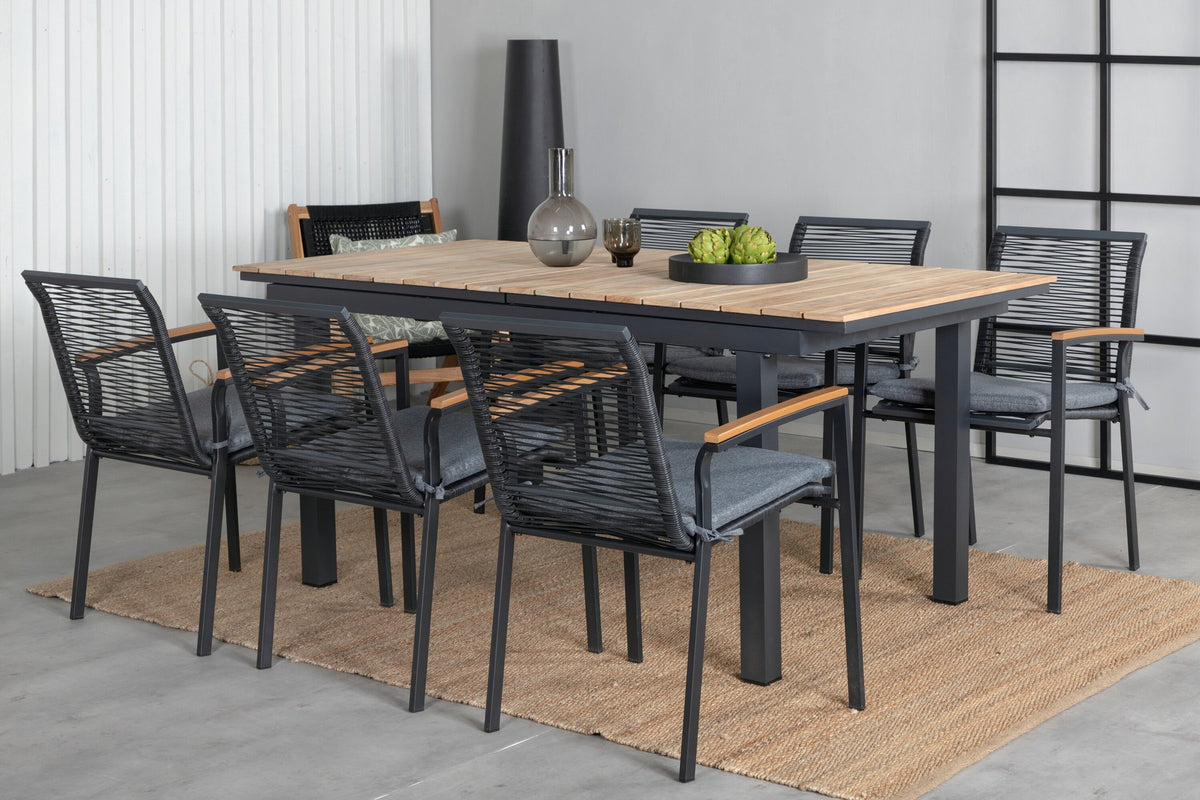 Foto eines schwarzen 2er-Stuhlsets mit Aluminiumgestell und Polyesterbezug neben einem rechteckigen Teak-Esstisch in Natur mit Stahlbeinen.