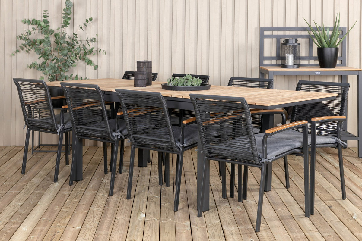 Foto eines schwarzen 2er-Stuhlsets mit Aluminiumgestell und Polyesterbezug neben einem rechteckigen Teak-Esstisch in Natur mit Stahlbeinen.