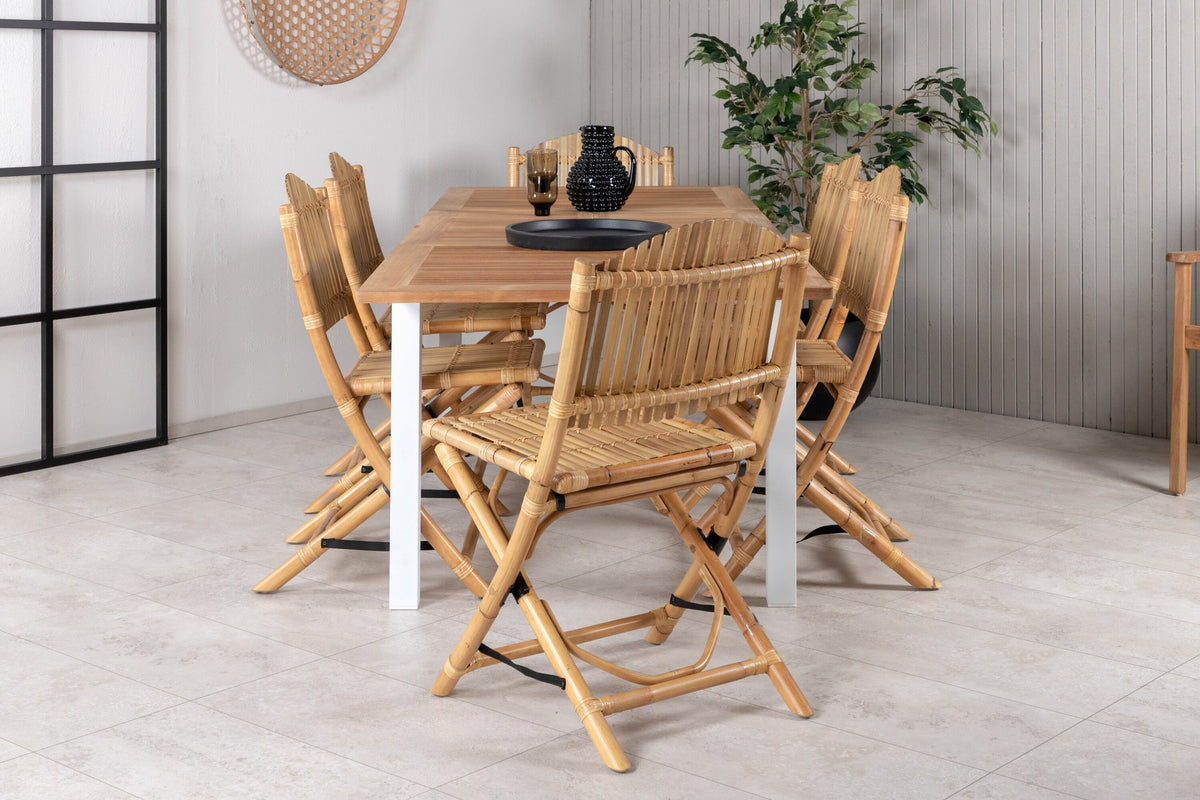 Foto zeigt einen Cafe Stuhl mit Rattan-Beinen und Stoffbezug in Natur sowie einen rechteckigen Teakholz-Esstisch mit weissem Aluminiumgestell.