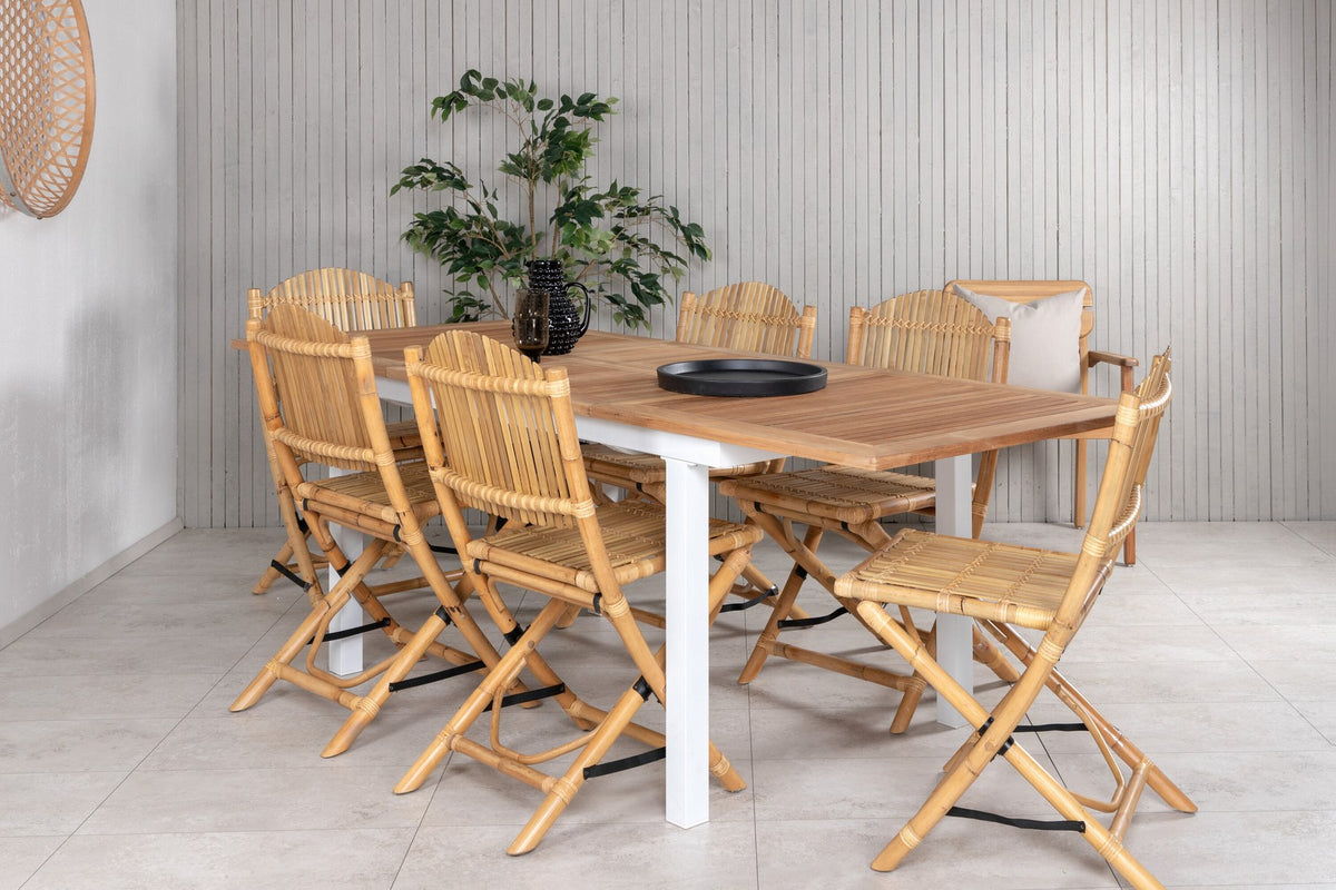 Foto zeigt einen Cafe Stuhl mit Rattan-Beinen und Stoffbezug in Natur sowie einen rechteckigen Teakholz-Esstisch mit weissem Aluminiumgestell.