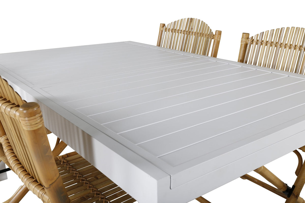 Aluminium-Caféstuhl in Natur mit Baumwoll-Polyester-Bezug neben rechteckigem Esstisch mit weisser Aluminium-Tischplatte und Rattanbeinen.