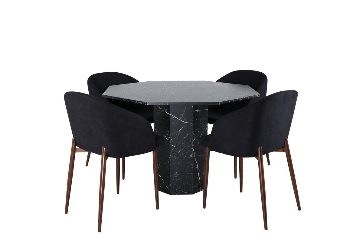 Zwei schwarze Esszimmerstühle mit Nussbaum-Beinen und Polyester-Sitzfläche neben rundem Esstisch Ø110cm mit schwarzer MDF-Platte und Stahlbeinen.