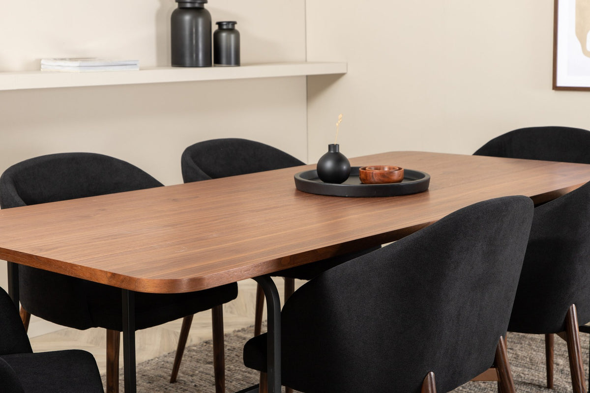 Esszimmerset Uno: rechteckiger Tisch mit MDF-Furnier-Platte in Nussbaum und schwarzem Stahlgestell, dazu Arch Stühle mit Polyesterbezug.