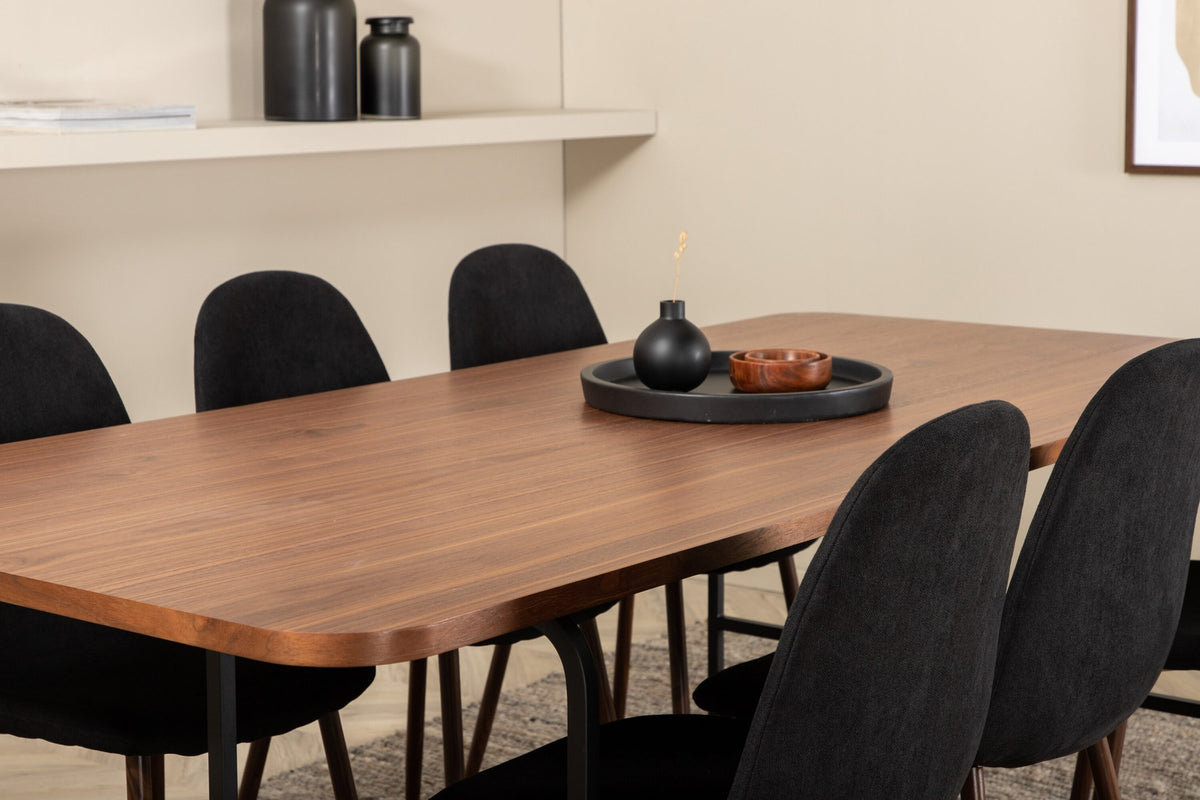 Rechteckiger Esstisch mit Nussbaum-Furnierplatte aus MDF und schwarzem Stahluntergestell, umgeben von sechs gepolsterten Polar Stühlen mit schwarzem Polyesterbezug.