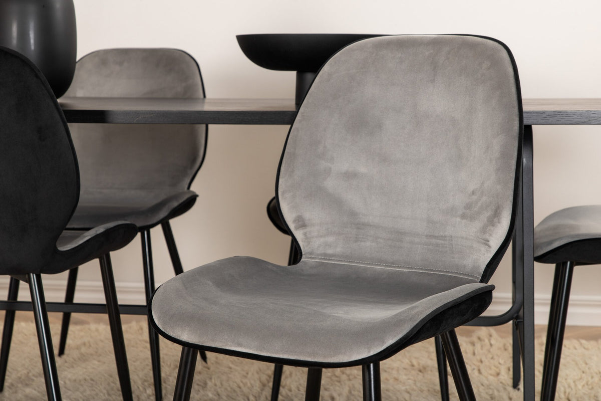 Zwei graue Esszimmerstühle mit Samtbezug und Eisenbeinen neben einem rechteckigen schwarzen Esstisch aus MDF mit Furnier und Metallgestell.