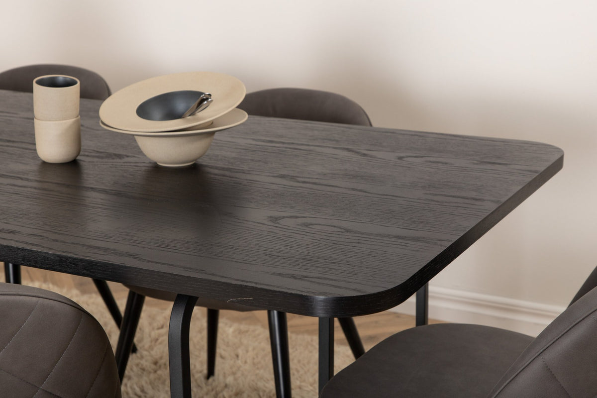 Esszimmerset Uno & Velvet: rechteckiger Esstisch mit schwarzer MDF-Furnier-Platte und Metallgestell, dazu Stühle mit grauem Samtbezug und Eisenbeinen.