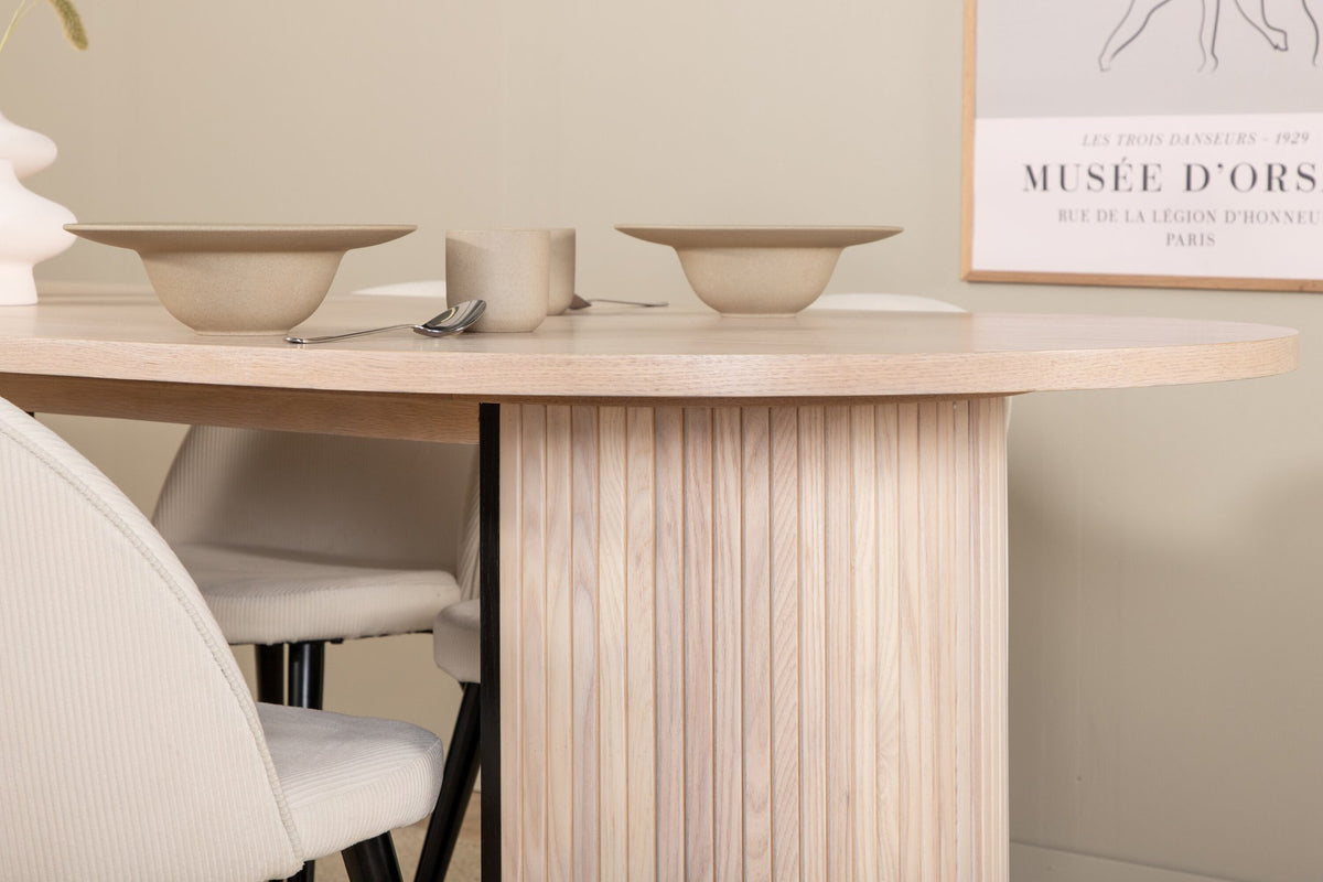 Ovaler Esstisch mit weiss lasierter MDF-Tischplatte und vier Samtstühlen mit schwarzen Stahlbeinen, cremefarbenes Esszimmerset.