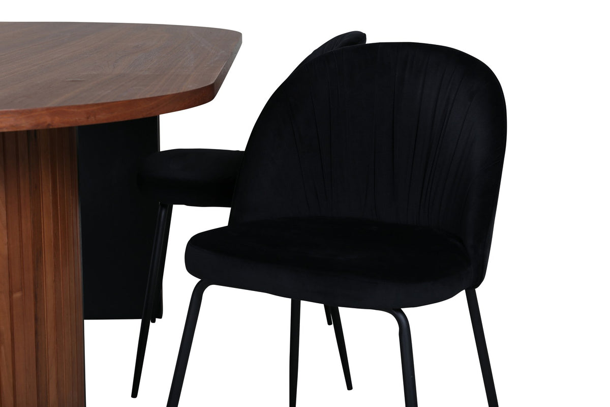Zwei schwarz gepolsterte Esszimmerstühle mit Samtbezug und Metallgestell neben ovalem Esstisch mit Nussbaum-Furnierplatte und Stahlgestell.