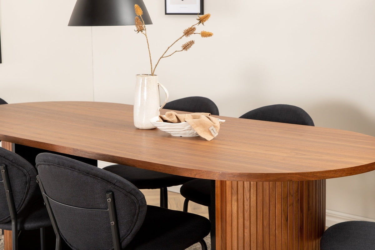 Ovaler Esstisch aus Nussbaum-MDF mit Furnier und Stahlbeinen, dazu zwei schwarze Polsterstühle mit Metallbeinen im Set.