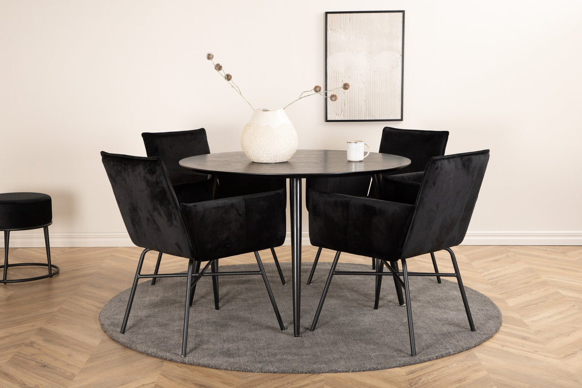 Rundes Esszimmerset Dipp mit schwarzer MDF-Tischplatte, Ø115 cm, und vier Petra-Stühlen mit schwarzem Samtsitz und Eisenbeinen.