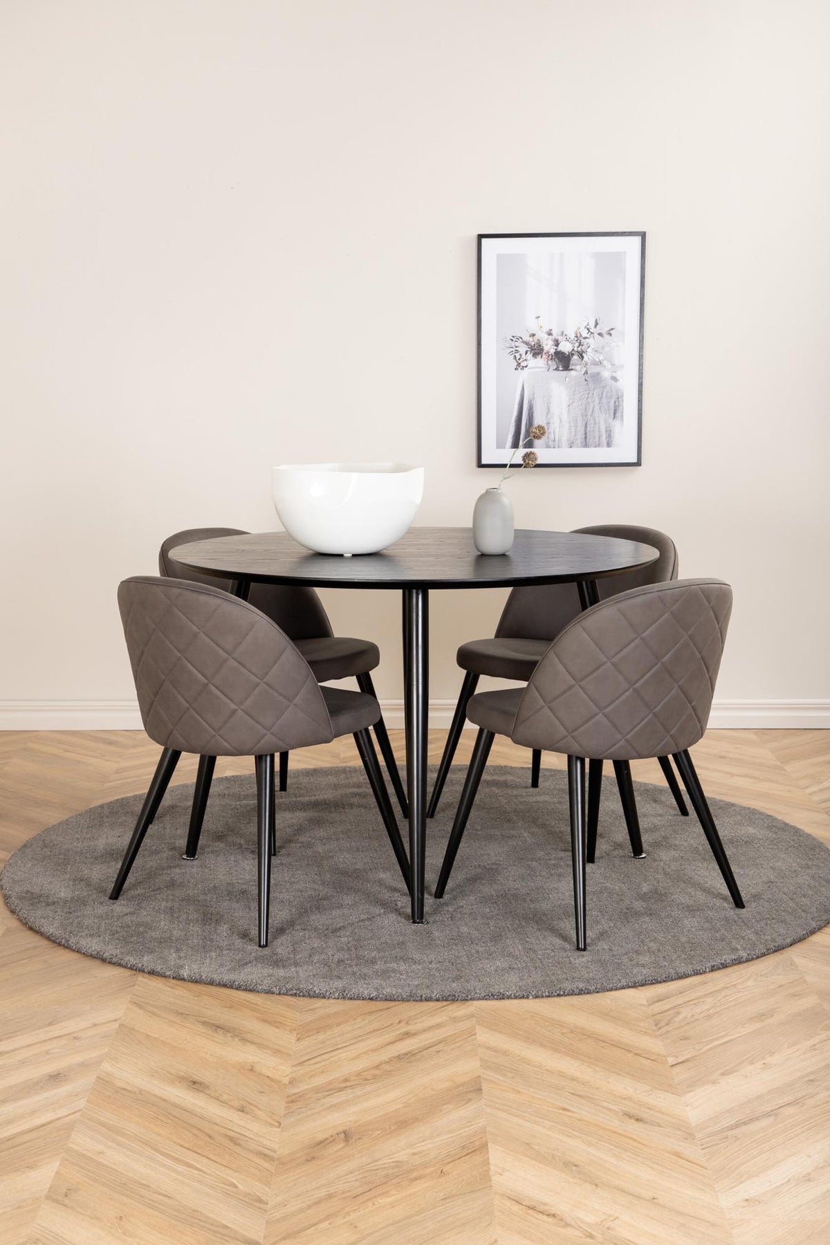 Rundes Dipp Esszimmerset: Esstisch ⌀115 cm mit schwarzem Furnier und schwarzen Beinen, dazu vier Velvet-Stühle mit schwarz-grauem Mikrofaserbezug.