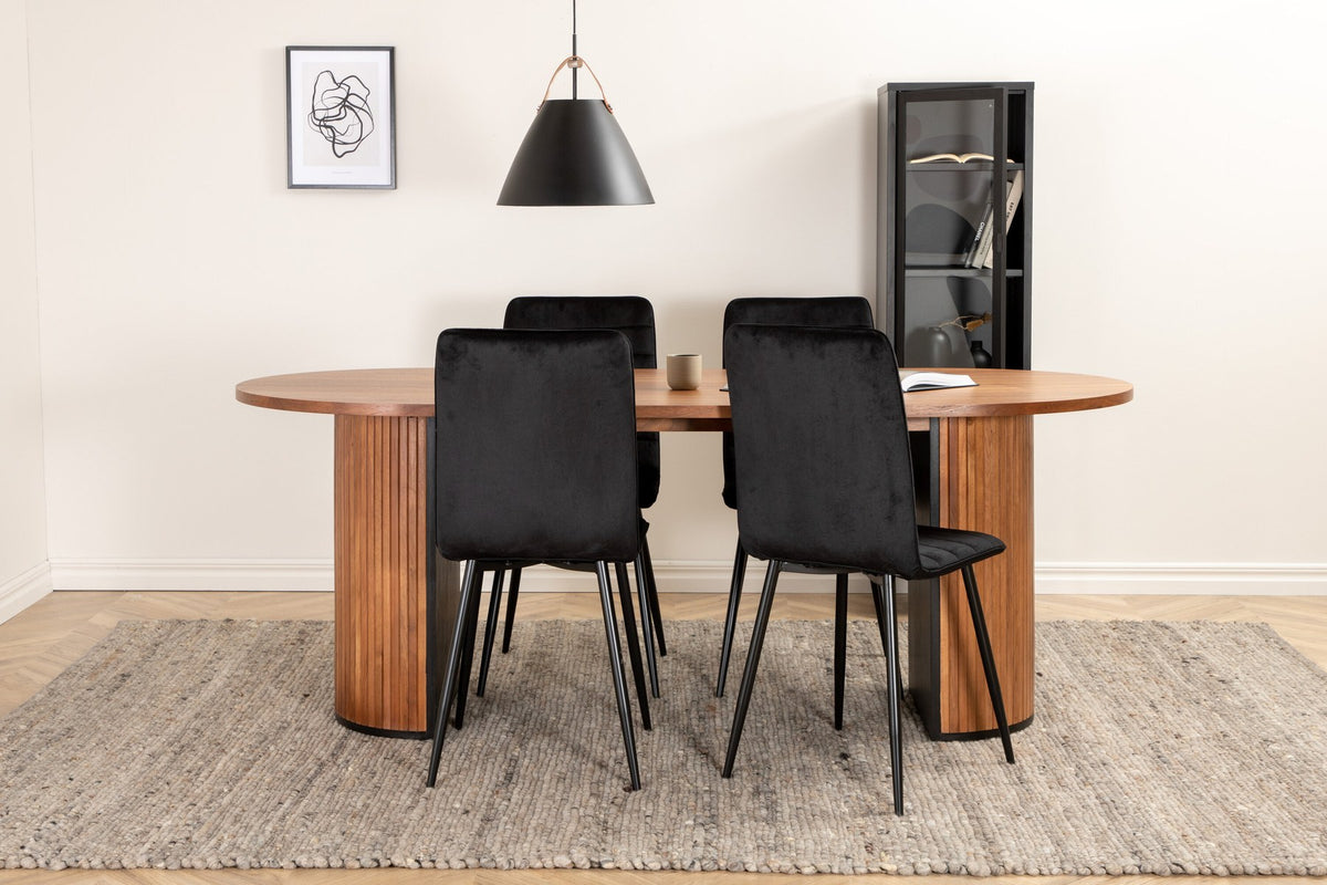 Ovaler Esstisch mit Nussbaum-Tischplatte aus MDF und Furnier sowie zwei schwarze Esszimmerstühle mit Samtsitz und schmalen Beinen.