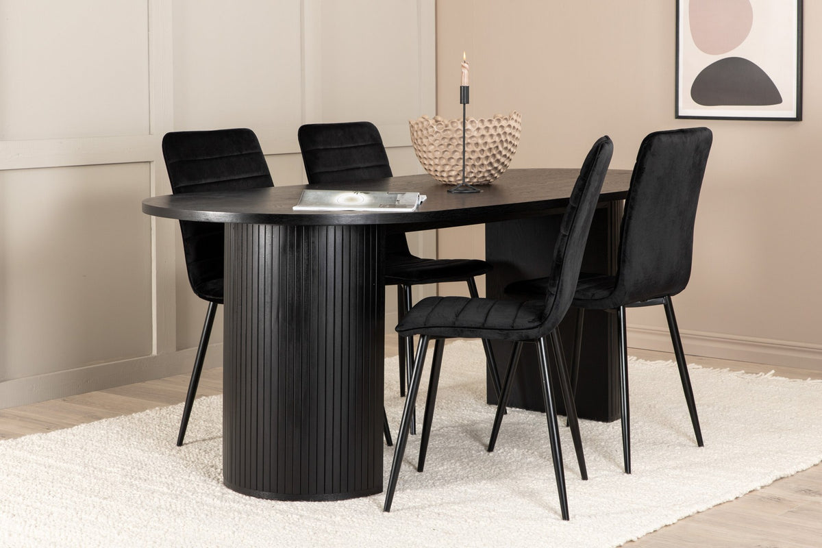 Ovaler schwarzer MDF-Esstisch mit gerippten Gestellbeinen und Esszimmerstühlen mit schwarzen Samtsitzen und schmalen Eisenbeinen.