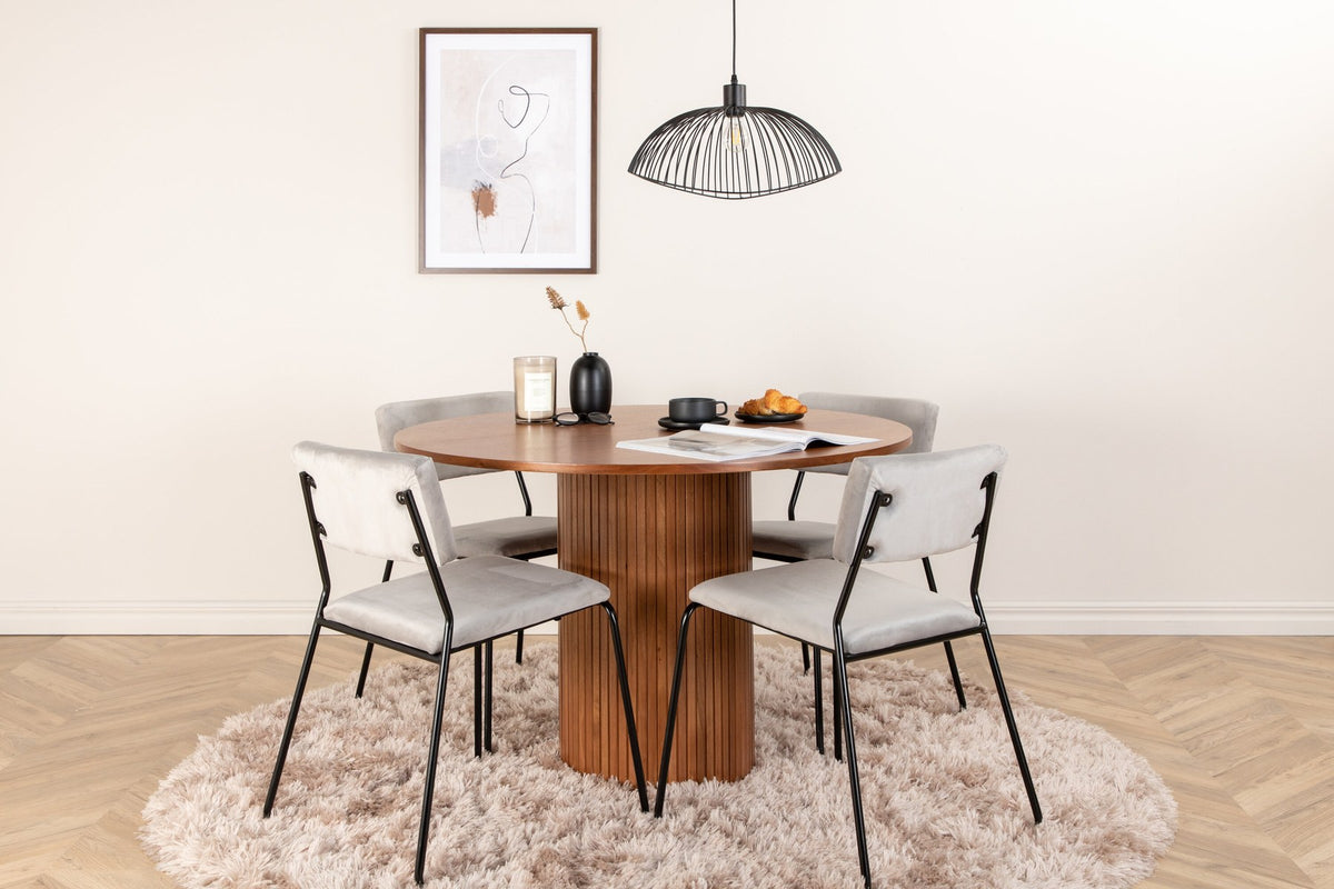 Zwei graue Esszimmerstühle mit schwarzem Metallgestell neben einem runden Esstisch aus Nussbaum-MDF mit Furnier, Durchmesser 110cm.