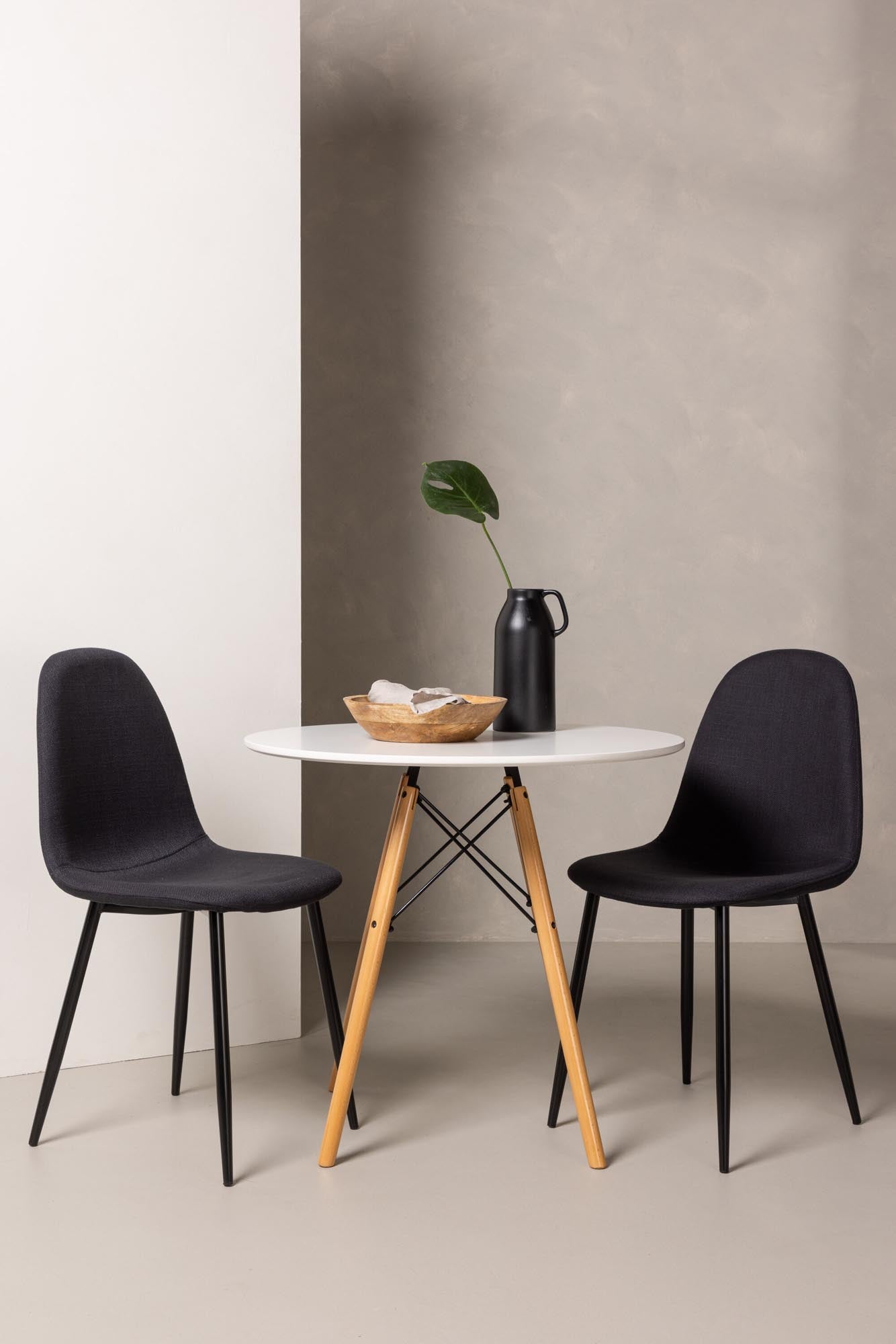 Elegantes Danburi Esszimmerset: runder Tisch aus weissem MDF, Buchenholzbeine, Polar-Stühle mit schwarzer Polsterung.