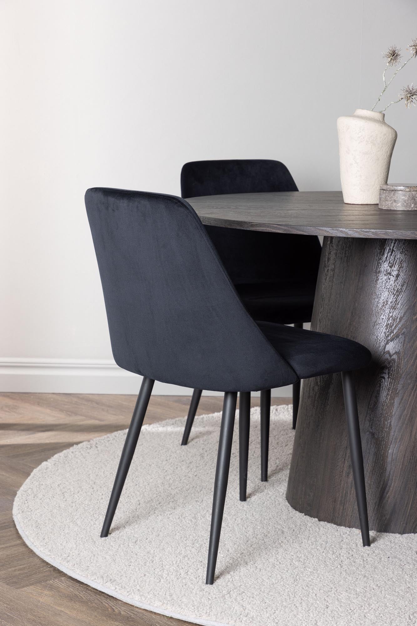 Entdecken Sie das Lanzo Esszimmerset + Night: Ein stilvolles Set mit einem eleganten runden Tisch und bequemen Samtstühlen für gesellige Runden.